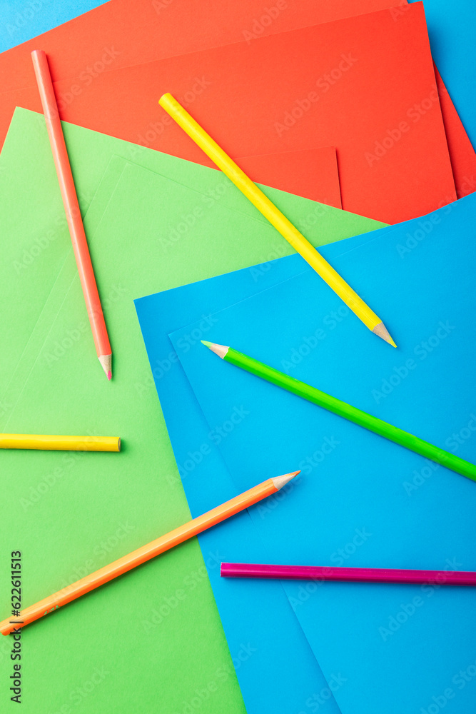 Vertical image of colored pencils and sheets of paper as background Vertical image of colored pencils and sheets of paper as background