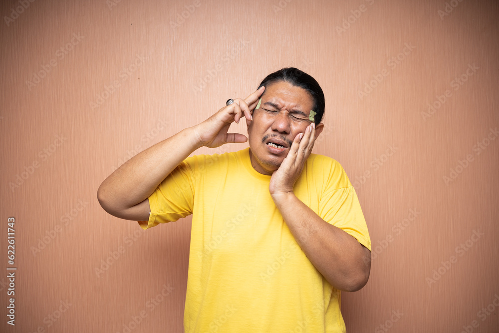 asian old man feeling headache migraine and toothache with clenching head gesture in plain background isolated asian old man feeling headache migraine and toothache with clenching head gesture in plain background isolated
