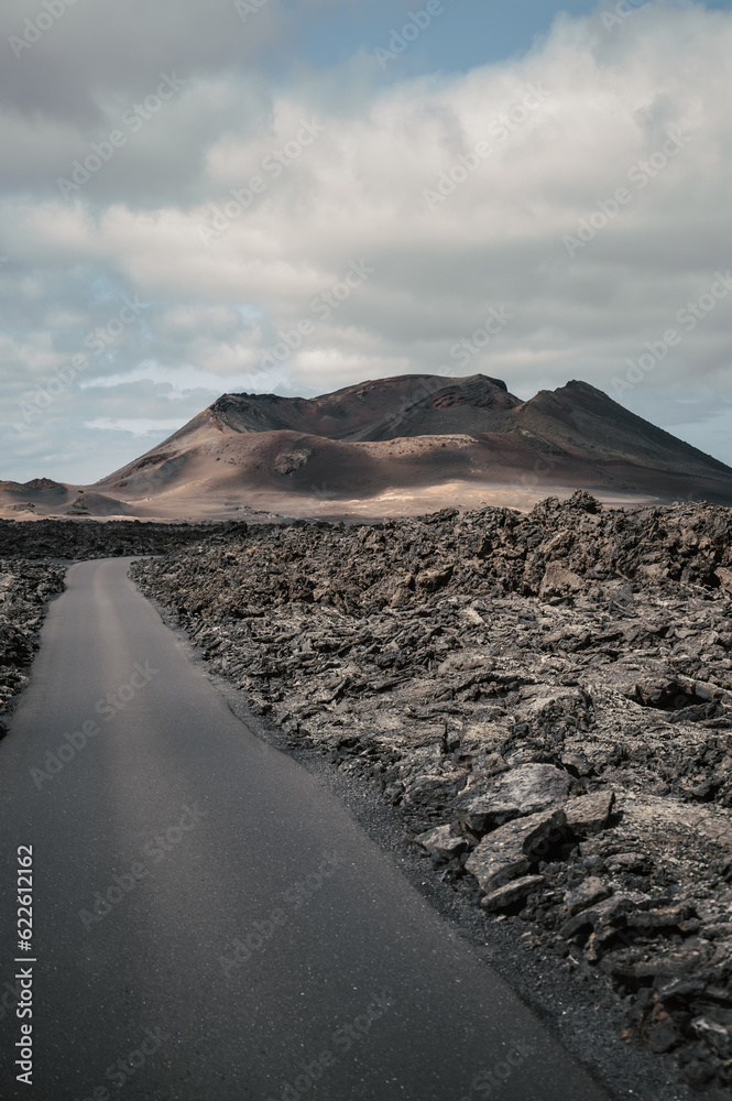 Carretera entre rocas volcánicas con el volcán de fondo