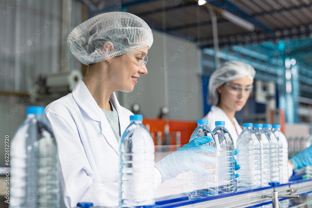 worker in drinking water factory. women workers caucasian labor in beverage clean production conveyor belt mineral water manufactory. worker in drinking water factory. women workers caucasian labor in beverage clean production conveyor belt mineral water manufactory.