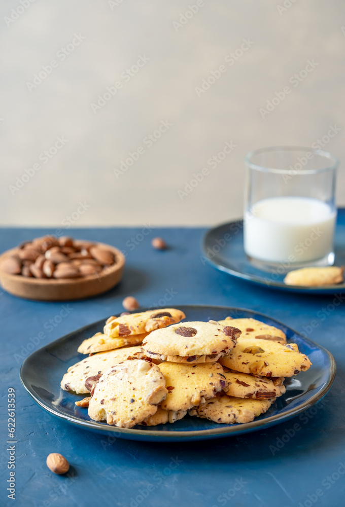 Florence cookies or Fiorentine biscuits with almonds on blu plate, almonds, glass of milk. Blue and grey background Florence cookies or Fiorentine biscuits with almonds on blu plate, almonds, glass of milk. Blue and grey background