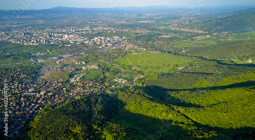 Panoramic view of Sofia, the capital of Bulgaria from a height from a drone. At the foot of Vitosha Mountain in early spring the whole forest is green