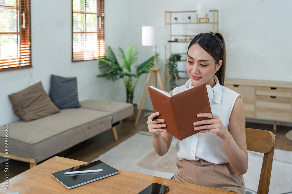 Obraz premium Attractive young woman sits in and comfortable living room enjoying reading a book