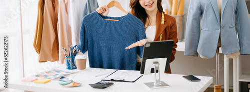 Fashion blogger concept, Young Asian women selling clothes on video streaming.Startup small business SME, using smartphone or tablet taking receive and checking.