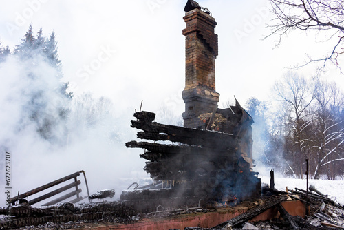 Smoke on the ashes, brick chimney in smoke after a fire in a wooden building