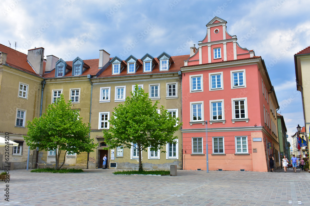 Old architectural buildings with colorful walls. Cityscape with houses. Trees around. Summer sunny day with blue sky. Poland, Poznan, June 2022