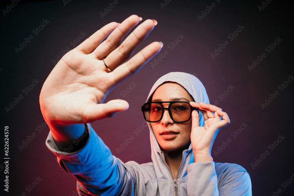 woman wearing sport wear jacket and sunglasses smirk saying no and holding sunglasses in dark background woman wearing sport wear jacket and sunglasses smirk saying no and holding sunglasses in dark background