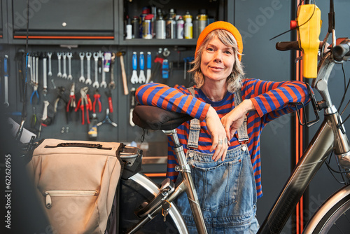Smiling woman technician posing with bicycle at shop sells