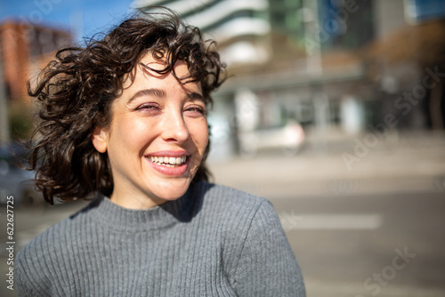 Beautiful young woman looking at camera and smiling outside in the city