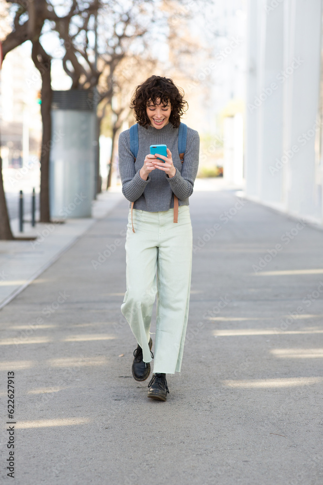 Fashionable young woman walking outside texting on cellphone Fashionable young woman walking outside texting on cellphone