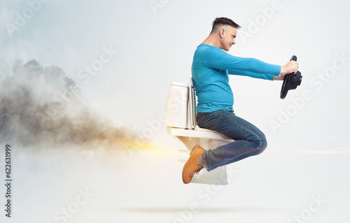 Confident funny man is flying sitting on the toilet, holding a car steering wheel, smoke exhaust from behind, on a light background