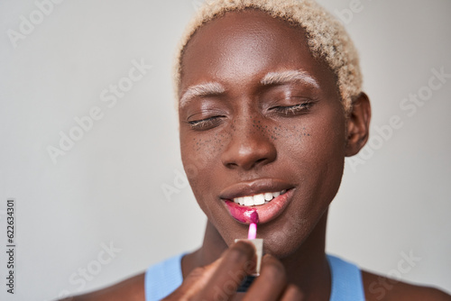 Multiracial visagist preparing magnificent makeup and applying pink lipstick