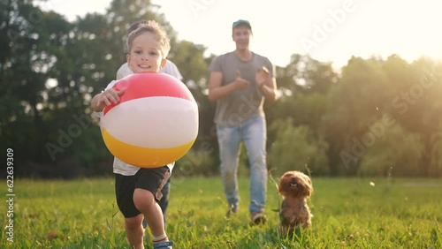 happy family. children and parents run in the park play ball. happy family kid concept. boy runs on grass in park holding the ball. group of children and parents family play in the park run dream