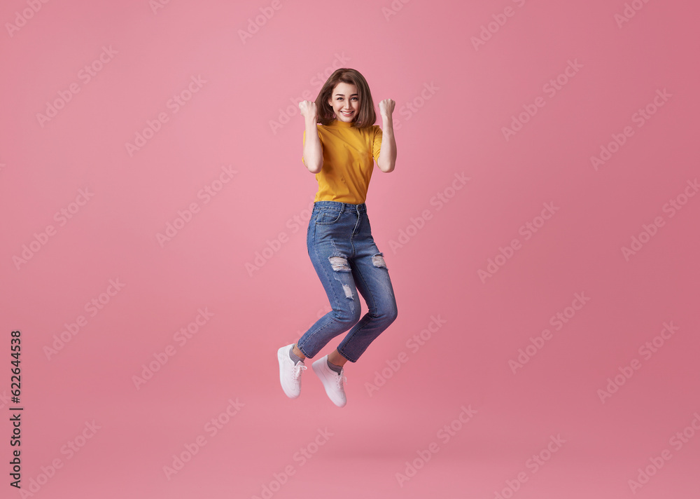 Happy woman smiling and jumping while celebrating success isolated over pink background. Happy woman smiling and jumping while celebrating success isolated over pink background.