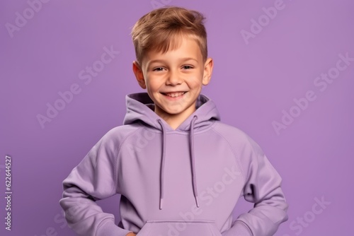 Portrait of a cheerful little boy in a purple hoodie on a purple background photo
