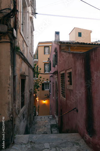 Cosy narrow street with pink and yellow buildingsin Corfu old town, Greece photo