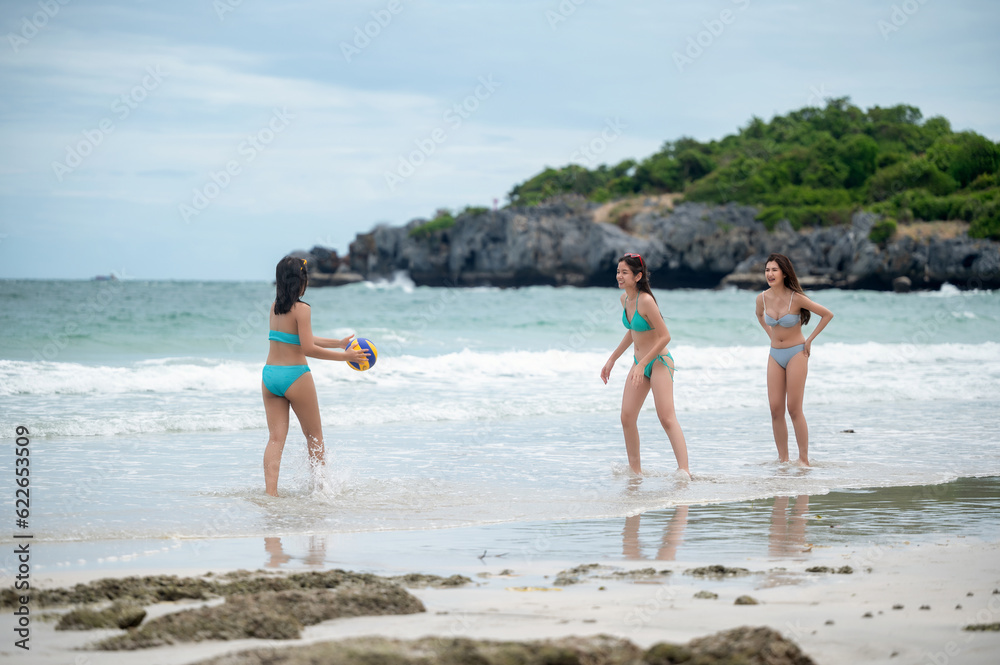 Group of woman traveler in bikini playing ball beach on the sea beach, enjoy moment on the sea summer