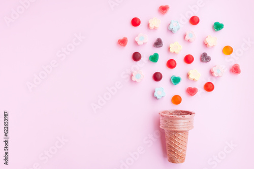 Multicolored Marshmallows and jelly candy out of ice cream cone on pink background, Flower Shaped Marshmallows and jelly candy heart shaped