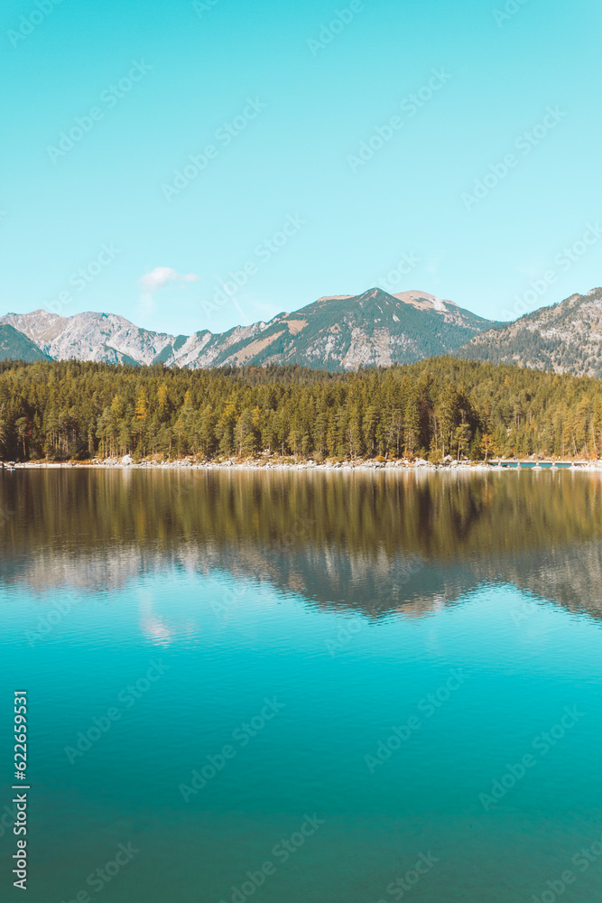 Calm relaxing landscape with Alpine mountains and autumn forest in Bavaria, Germany. Reflection in blue water