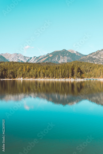 Calm relaxing landscape with Alpine mountains and autumn forest in Bavaria, Germany. Reflection in blue water