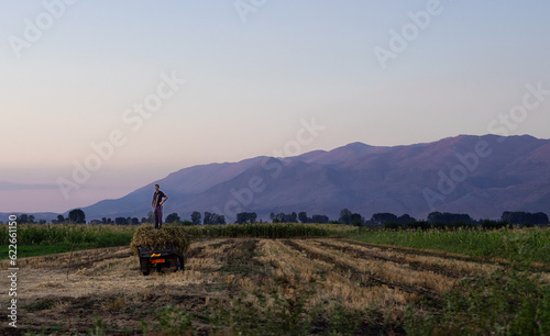 Beautiful scene of an Albania farmer on his land with a picturesque mountain range and sunset behind him
