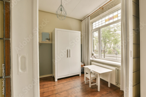 a room with wood flooring and white cupboards in front of a window that is open to the outside