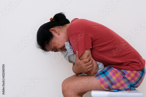 Closeup shot of a woman in casual clothes hugging pillow looking sick
