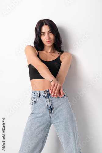 Young beautiful woman in jeans and a tank top on a white background
