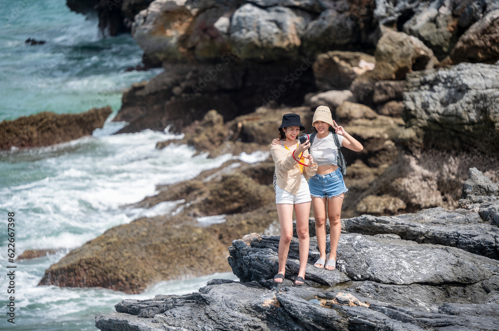 Women traveler enjoy the trip of hiking to the natural cliff in the sea, summer moment on trip traveling