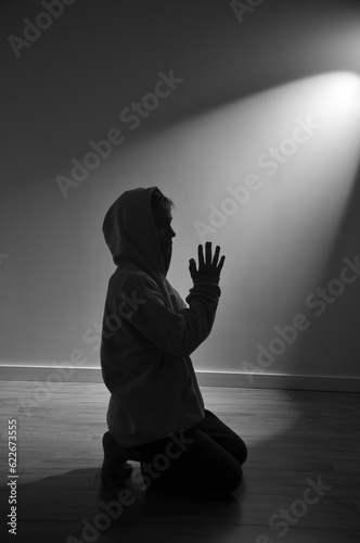  menino fazendo oração de joelhos no chão recebendo iluminação 