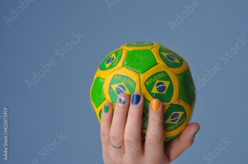 m  os segurando bola do brasil  unhas pintadas em manicure com cores do brasil  simbolo verde e amarelo cores da bandeira do brasil 