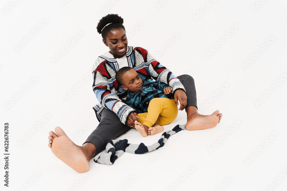 Black young woman playing with her son while sitting on floor Black young woman playing with her son while sitting on floor