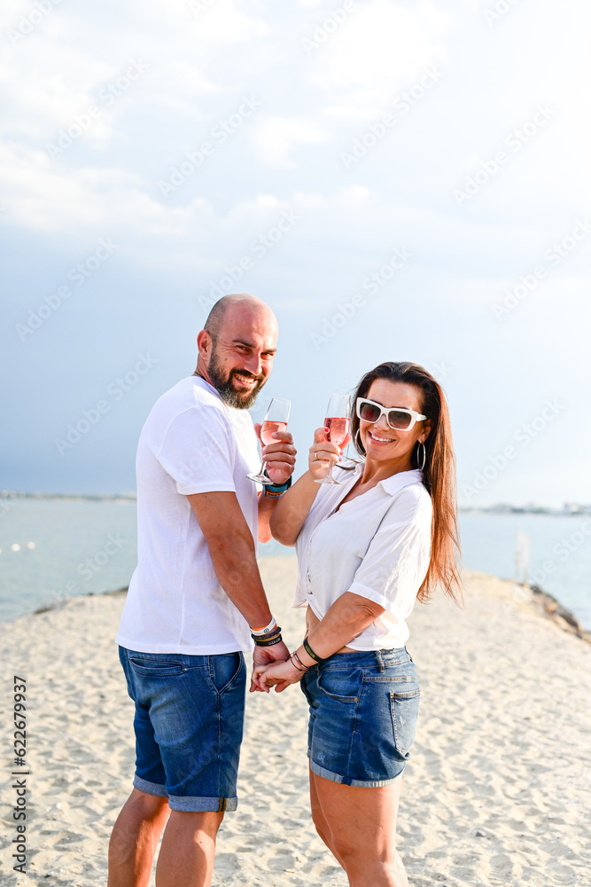  Portrait of a happy Smiling beautiful young couple in while standing at the beach.Happy casual couple holding hands and hugging and walking at the beach 