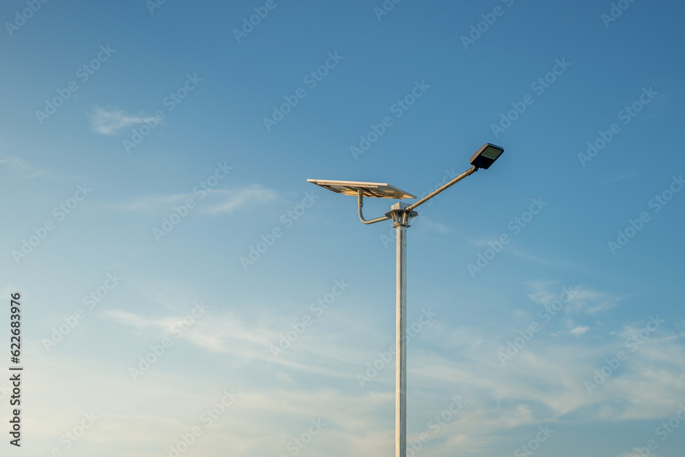 A modern street LED lighting pole.Public city light with solar panel powered on blue sky with clouds A modern street LED lighting pole.Public city light with solar panel powered on blue sky with clouds
