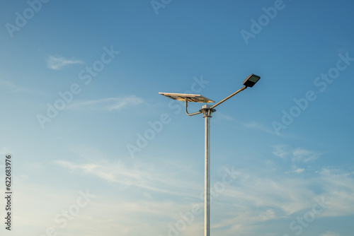 A modern street LED lighting pole.Public city light with solar panel powered on blue sky with clouds