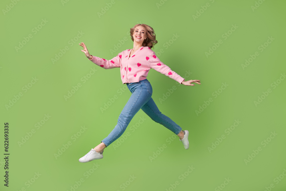 Full length profile photo of active carefree cheerful person jumping run have good mood isolated on green color background Full length profile photo of active carefree cheerful person jumping run have good mood isolated on green color background