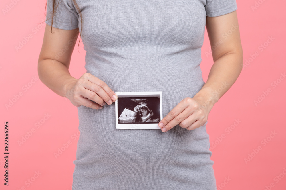 Happy Pregnant Woman standing smile holding ultrasound image stroking big belly with love isolated on pink background,Pregnancy of young woman enjoy with future life,Motherhood and Pregnant Concept Happy Pregnant Woman standing smile holding ultrasound image stroking big belly with love isolated on pink background,Pregnancy of young woman enjoy with future life,Motherhood and Pregnant Concept