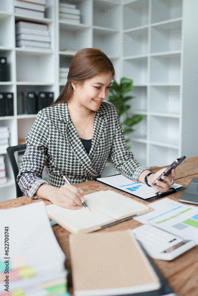 Consultant, advisor, Asian business woman working on the computer and using smartphone mobile talking work financial and marketing business planning company profits, marketing planning budget. Consultant, advisor, Asian business woman working on the computer and using smartphone mobile talking work financial and marketing business planning company profits, marketing planning budget.