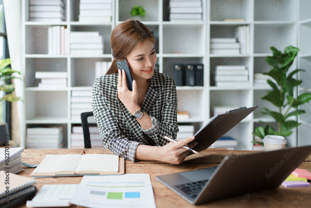 Consultant, advisor, Asian business woman working on the computer and using smartphone mobile talking work financial and marketing business planning company profits, marketing planning budget. Consultant, advisor, Asian business woman working on the computer and using smartphone mobile talking work financial and marketing business planning company profits, marketing planning budget.