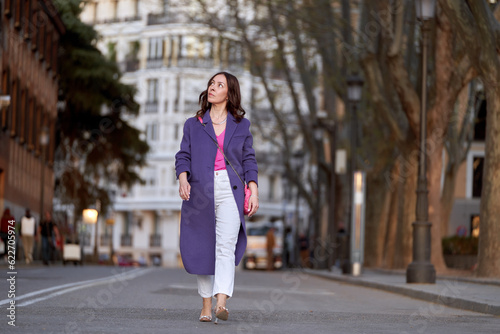 Stylish woman smiling while walking outdoors on the street.