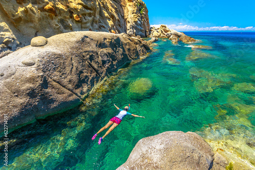 Top view of snorkeler in Sant 'Andrea beach Cote Piane side with rocks and coves, Elba island. Woman in clear waters of Tyrrhenian sea on holiday travel in Italy.Saint Andrew is popular seaside resort photo