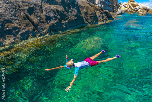 Top view of snorkeler in Sant 'Andrea beach Cote Piane side with rocks and coves, Elba island. Woman in clear waters of Tyrrhenian sea on holiday travel, Italy. Saint Andrew is popular seaside resort.