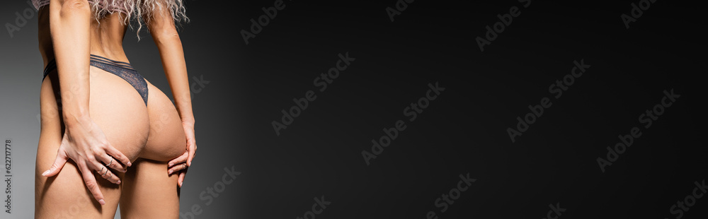 sexuality and fashion, cropped view of provocative woman with toned body touching sexy buttocks while posing in lace panties on black and grey background, banner with copy space sexuality and fashion, cropped view of provocative woman with toned body touching sexy buttocks while posing in lace panties on black and grey background, banner with copy space