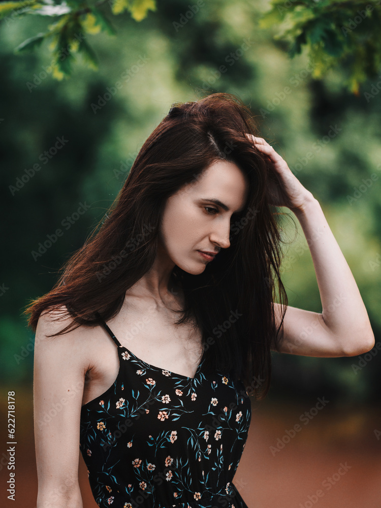 Young beautiful woman with long hair in a dress posing among the trees in the park, sensual portrait Young beautiful woman with long hair in a dress posing among the trees in the park, sensual portrait