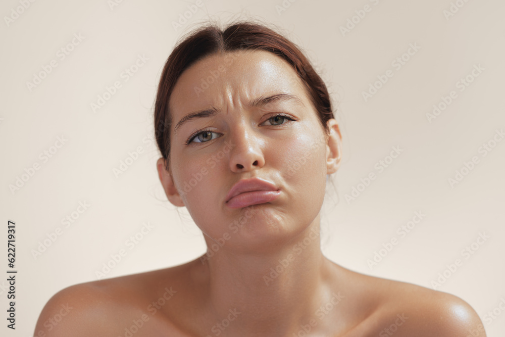 Disappointed Funny Cute Girl Face on Beige Studio Background. Disappointed Funny Cute Girl Face on Beige Studio Background.