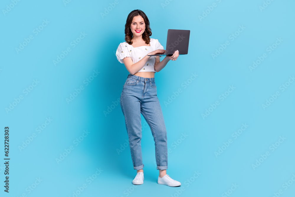 Full body portrait of pretty positive lady use wireless netbook coworking networking isolated on blue color background Full body portrait of pretty positive lady use wireless netbook coworking networking isolated on blue color background