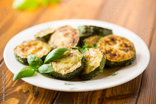 zucchini fried in circles with spices and herbs, in a plate .