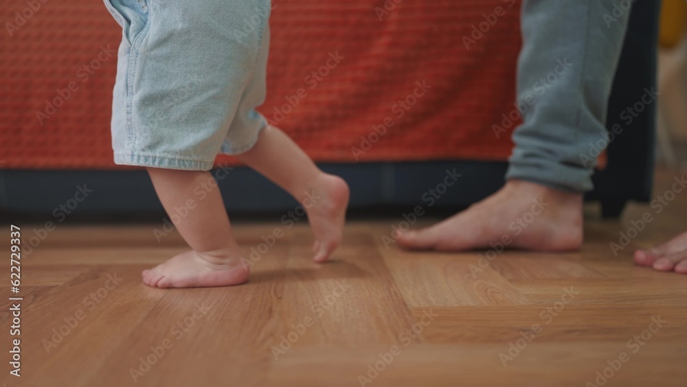 baby first steps. daddy a teaches baby toddler son to take first steps. happy family kid dream concept. baby indoors learning to walk father holding child hands. lifestyle fathers day concept