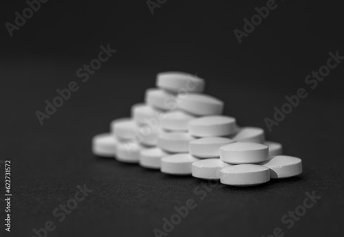 White tablets close-up on a black background with copy space. The concept of protecting the body from bacteria and viruses.