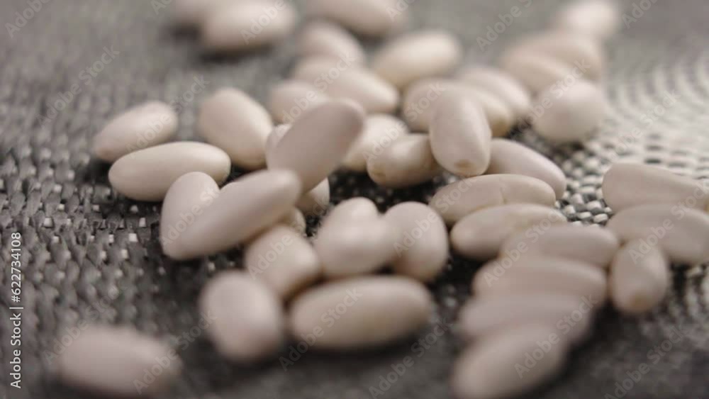 White kidney beans falling in slow motion on a wicker surface. Vegetable protein and fiber. Macro shot. Rotation White kidney beans falling in slow motion on a wicker surface. Vegetable protein and fiber. Macro shot. Rotation